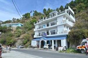 a white building on the side of a hill at Hotel Vasundhara Palace in Chamba