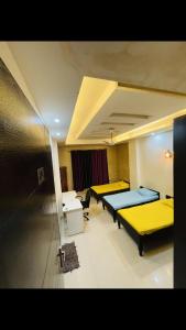 three beds in a room with yellow beds in it at StayHolic in Ghaziabad