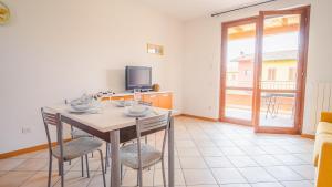 comedor con mesa, sillas y TV en Garda Orange Apartment - Italian Homing, en Desenzano del Garda