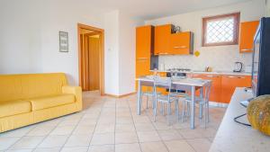 cocina con armarios naranjas y sofá amarillo en Garda Orange Apartment - Italian Homing, en Desenzano del Garda