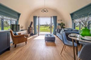 een woonkamer met een blauwe bank en een tv bij The Nissen Hut at Green Valley Farm in Laxfield