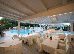 un ristorante con tavoli e sedie bianchi e una piscina di Hotel Sa Pedra a Murta Maria