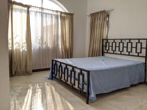 a bedroom with a bed with blue sheets and a window at Beautiful Home In Secure Township in Accra