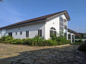 a white building with a cobblestone driveway in front of it at Beautiful Home In Secure Township in Accra