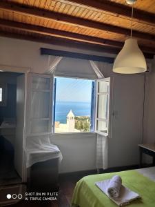 a bedroom with a window with a view of the ocean at Mykonos Rooms in Agios Stefanos