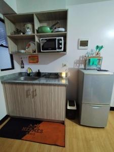 una pequeña cocina con fregadero y microondas en Imus Cavite Stayction - 1 Bedroom Condo Unit - Urban Deca Homes - Olive Bldg en Imus