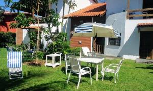 eine Gruppe Stühle, ein Tisch und ein Regenschirm in der Unterkunft Casanapraia Bertioga in Bertioga