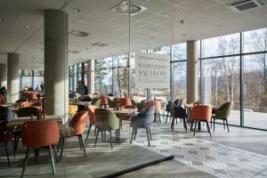 a restaurant with tables and chairs and windows at Złoty Horyzont Resort Szklarska Poręba in Szklarska Poręba