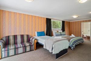 a hotel room with two beds and a couch at Pool House- Springfield in Rotorua