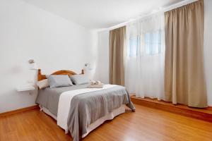 een witte slaapkamer met een bed en een raam bij Apartamento Aka in La Orotava