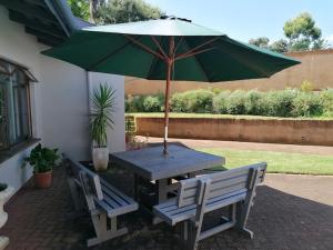a picnic table with a green umbrella and two benches at Fair Haven Guest Suite Self-catering in Marina Beach