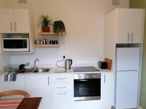 a white kitchen with a sink and a refrigerator at Fair Haven Guest Suite Self-catering in Marina Beach