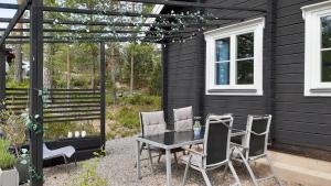 a table and chairs in front of a black house at Fröya Timber Cottage in Arvika