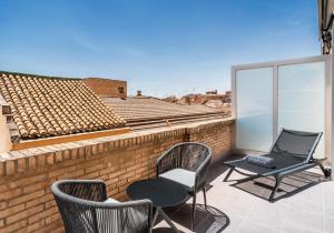 d'une terrasse avec 2 chaises et une table sur un mur en briques. dans l'établissement Barceló Carmen Granada, à Grenade