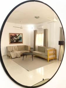 a mirror reflecting a living room with a couch and a table at Appartement - Le Grège in Ouagadougou