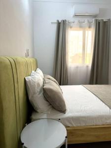 um quarto com uma cama com almofadas e uma janela em Appartement - Le Grège em Ouagadougou