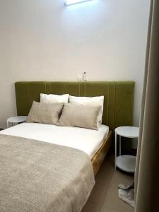 uma cama com uma cabeceira verde num quarto em Appartement - Le Grège em Ouagadougou