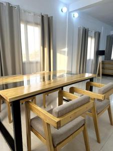 uma mesa de madeira com 2 cadeiras de madeira e uma mesa de madeira com janelas em Appartement - Le Grège em Ouagadougou