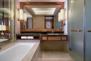 a bathroom with a tub and a sink and a mirror at Sheraton Grand Zhengzhou Hotel in Zhengzhou