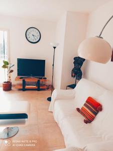 ein Wohnzimmer mit einem weißen Sofa und einem TV in der Unterkunft Un coin de campagne in Le Puy-Sainte-Réparade
