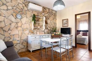 a living room with a table and a stone wall at Casa Dorca 1 in Conil de la Frontera