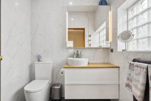 a white bathroom with a toilet and a sink at Spacious home near Glenelg in South Plympton +6 photos