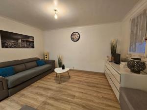 sala de estar con sofá y reloj en la pared en Appartement Proche Aéroport CDG, en Vaujours