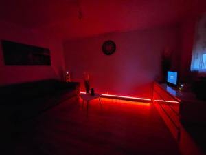 een woonkamer met rode verlichting in een kamer met een bank bij Appartement Proche Aéroport CDG in Vaujours