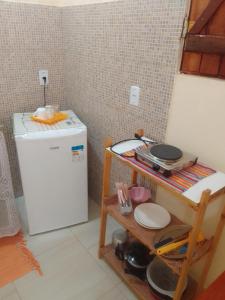 a kitchen with a refrigerator and a shelf with dishes at Flores do Riacho in São Miguel dos Milagres