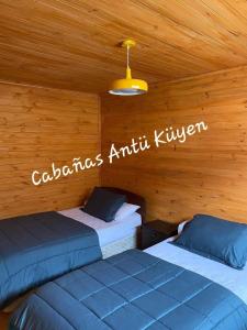 2 camas en una habitación con techo de madera en CABAÑAS ANTU KUYEN en Pichilemu