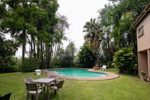a pool with chairs and a table in a yard at Crocodile Nest B&B in Nelspruit