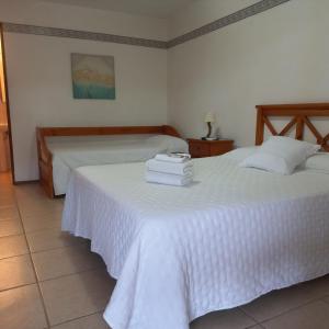 1 dormitorio con 2 camas con sábanas blancas en Hotel Marcos Dayman en Termas del Daymán