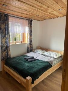 a bed in a bedroom with a wooden ceiling at Jaśkowa Chata Bieszczady apartament z basenem in Baligród