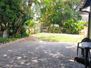 a patio with a bench and a yard with trees at Pompano Place Rest in Richards Bay
