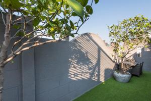 a wall with a tree casts a shadow on it at The Elite @ Thong Lor 25 in Bangkok