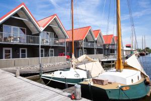 Dos barcos están atracados junto a una fila de casas. en Summio Havenresort Terherne en Terherne