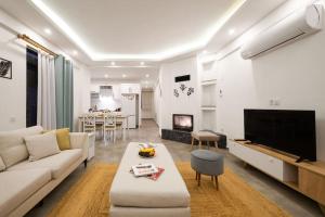 un salon avec un canapé blanc et une télévision dans l'établissement Villa Sazak Duo, à Gelemiş