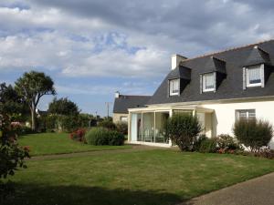 ein weißes Haus mit einem Garten mit Gras und Blumen in der Unterkunft Maison de la Presqu'île - 4 chambres avec Vue Mer in Lanmodez