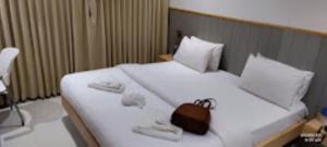 a bedroom with a large white bed with a purse on it at MAX PRIME, Madurai in Madurai