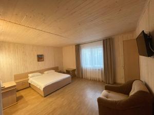 a bedroom with a bed and two chairs and a television at Karpatskyy in Rozluch