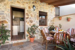 Un patio con mesa y sillas y un muro de piedra. en Casa Dorca, 2, en Conil de la Frontera