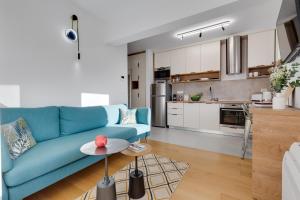 a living room with a blue couch and a kitchen at Tres Fenestras Zadar - private parking in Zadar