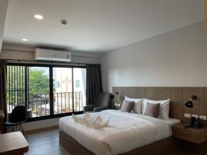 a bedroom with a large bed and a balcony at Nakara Hotel, Ubon Ratchathani in Ban Na Kham