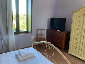 a bedroom with a bed and a tv and a dresser at Casale Neocastrum in Lamezia Terme