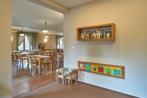 a dining room with tables and chairs and a book shelf at Hotel Toč in Lipova Lazne