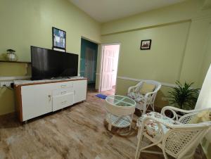 a living room with a flat screen tv and chairs at The Ark Guest House - Shillong in Shillong