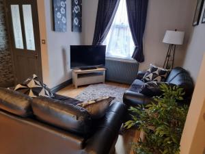 a living room with leather furniture and a flat screen tv at Cosy home in York in York