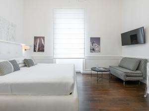 ein weißes Schlafzimmer mit einem Bett und einem Stuhl in der Unterkunft PLEY Cagliari Boutique Rooms in Cagliari