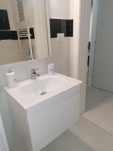 ein weißes Badezimmer mit einem Waschbecken und einem Spiegel in der Unterkunft Fiumicino Aeroporto Casa Vacanze Orchidea in Fiumicino