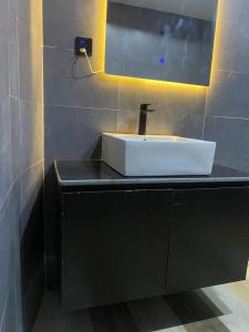 een badkamer met een witte wastafel op een zwart aanrecht bij Water Ripples Hotel Lekki in Lekki